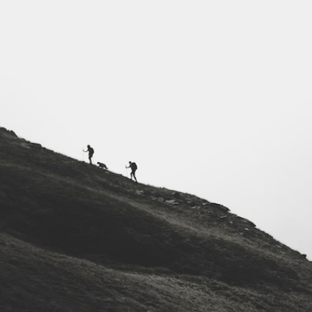 Two figures off in the distance walking up a large hill